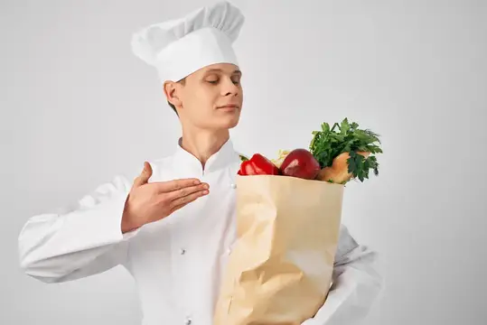 Мужчина в униформе шеф-повара с упаковкой продуктов занимается доставкой из ресторана