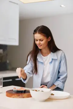 Молодая женщина готовит салат на светлой кухне