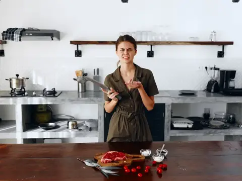 Молодая женщина с ножом кривится на кухне