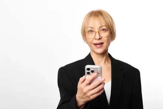 Пожилая женщина в очках фотографирует себя с помощью смартфона