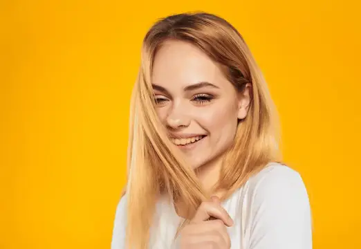 Светловолосая девушка улыбается на жёлтом фоне