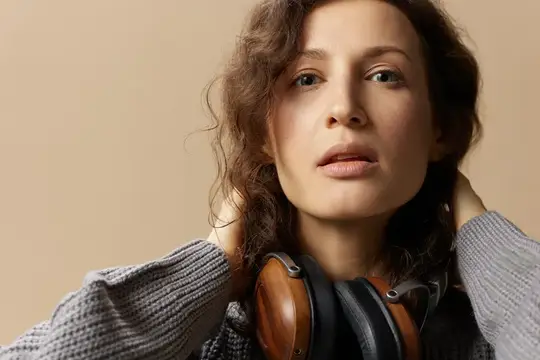 Молодая женщина с кудрявыми волосами слушает музыку в наушниках