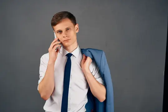 Деловой мужчина с пиджаком на плече и телефоном в руках