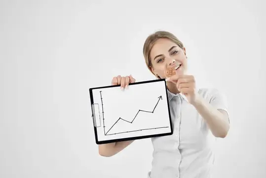 Улыбающаяся женщина показывает планшет с графиком роста и держит монету