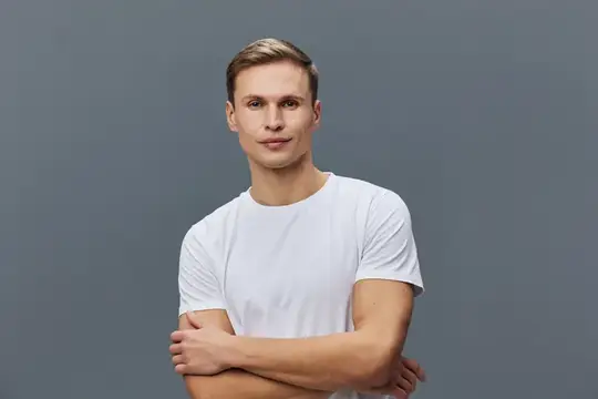 Уверенный молодой мужчина в белой футболке на сером фоне