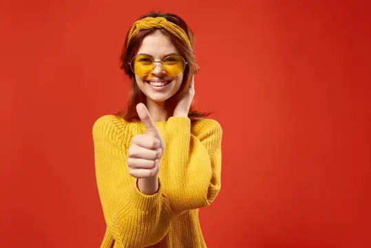Улыбчивая девушка в жёлтых очках показывает большой палец вверх