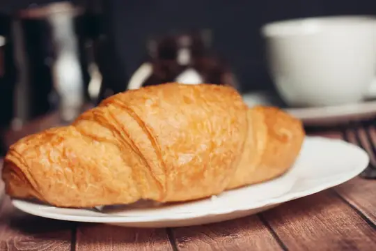 Круассаны на тарелке, чашка с напитком
