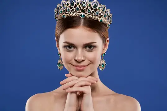 Красивая женщина с обнаженными плечами, украшениями и косметикой, обладающая привлекательным взглядом