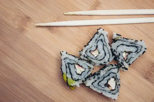 Роллы с лососем и палочки для суши на бамбуковой доске