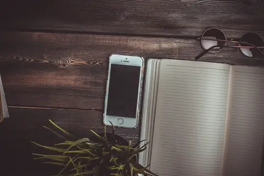 Смартфон, блокнот и очки на тёмном деревянном столе