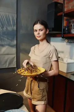 Молодая женщина держит тарелку с едой на кухне
