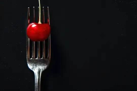 Это захватывающее изображение демонстрирует глянцевую вишню на серебряной вилке, красиво контрастирующую с темным фоном
