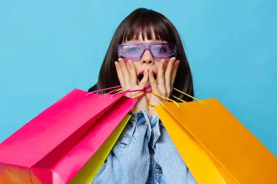 Удивлённая девушка в очках с разноцветными пакетами