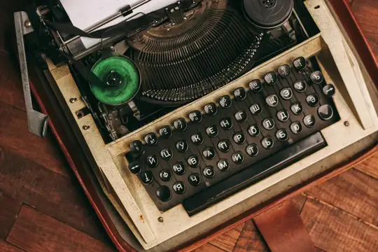 Винтажная пишущая машинка с клавишами на деревянном фоне и белый лист бумаги