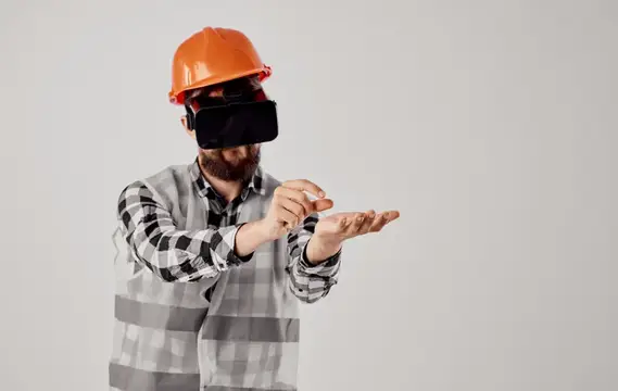 Архитектор в 3D-очках виртуальной реальности жестикулирует руками, на голове оранжевая каска
