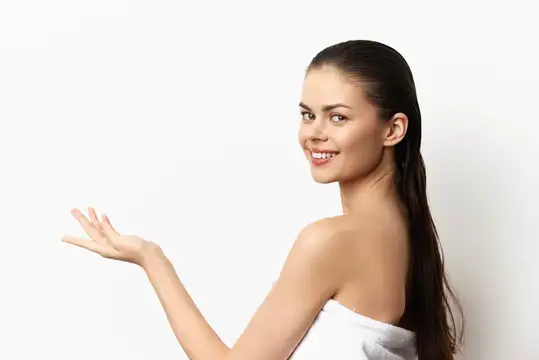 Улыбающаяся темноволосая девушка с полотенцем на плечах показывает рукой в сторону