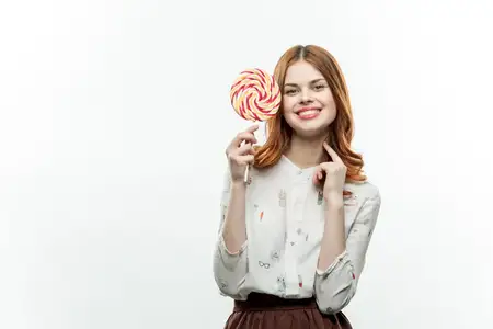 Женщина облизывает леденец на палочке, удовольствие, сладкая конфета, радость