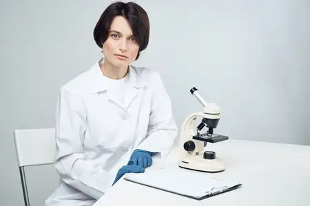 Женщина-лаборант работает с микроскопом, занимаясь научными исследованиями в студийных условиях