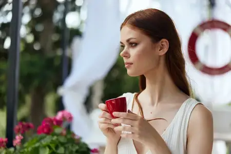 Симпатичная женщина пьет кофе на открытом воздухе