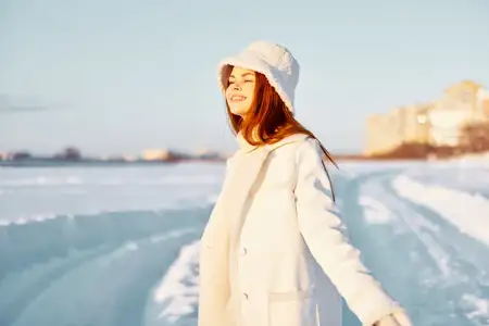 Симпатичная женщина в зимней одежде идет по снегу в холодную погоду, наслаждаясь отпуском и путешествием