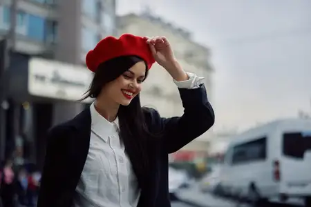Улыбающаяся женщина с деловой улыбкой идет по городу на фоне офисных зданий, одетая в стильную модную одежду и с макияжем, весенняя прогулка, путешествие