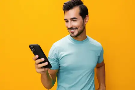Мужчина указывает, бизнес, улыбается, технологии, счастливый, образ жизни, общение, изолирован, смартфон, студия, жёлтый фон, сообщение, удивлён, улыбка, портрет, в очках
