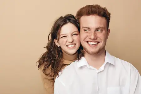 Улыбающиеся молодые мужчина и женщина в повседневной одежде делятся радостным моментом