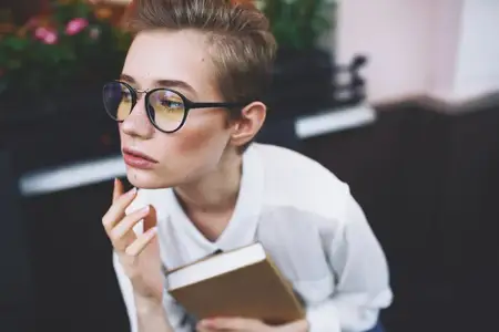 Девушка на улице держит в руках книгу, что символизирует образование
