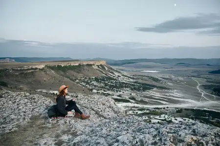 Безмятежная женщина смотрит на залитую лунным светом долину со скалистого уступа в сумерках