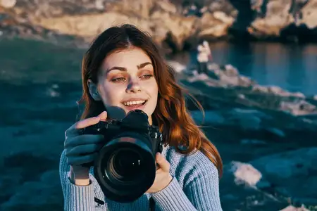 Жизнерадостная женщина-фотограф на открытом воздухе, скалистые горы, профессиональная работа, туризм
