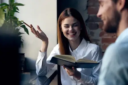 Деловая женщина в рубашке с книгой в руках рядом с мужчиной, офисная работа