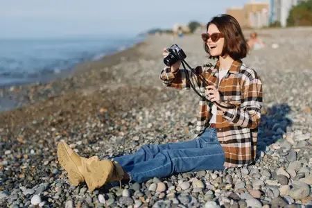 Непринужденная уличная съемка женщины-фотографа на галечном пляже