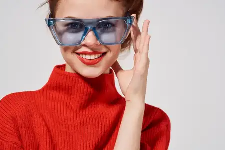 Красивая женщина в солнцезащитных очках современного стиля на светлом фоне