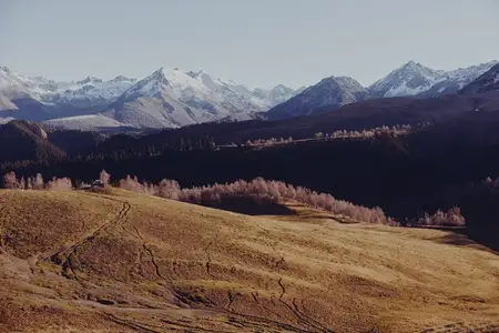 Осенний горный пейзаж во время путешествия, на заднем плане виднеются покрытые снегом зимние вершины