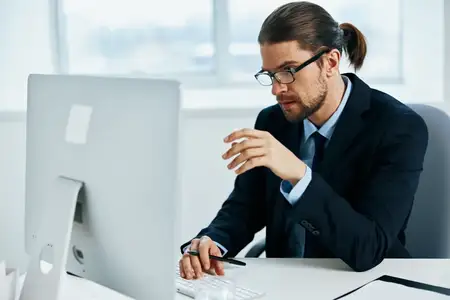 Бизнесмен сидит за столом перед компьютером