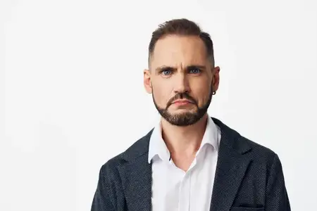 Изолированный цветной фон подчеркивает спокойный, но напряженный взгляд руководителя, изображая амбиции, надежность и уверенное лидерство в современной корпоративной обстановке