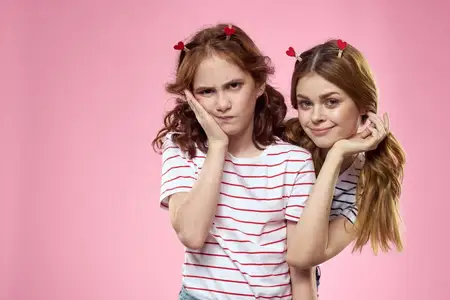 Счастливые девушки с модными украшениями на головах на розовом фоне, веселье, обрезанный вид, сёстры