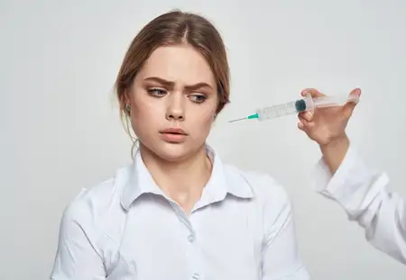 Шприц с жидкостью и пациентка в белой футболке, что указывает на проблемы со здоровьем