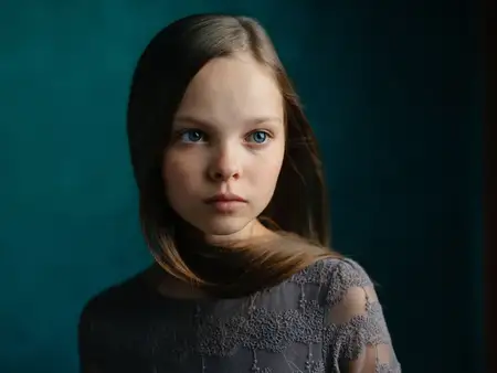 Милые маленькие девочки-модели на зеленом фоне, одетые в серые платья и с соответствующей прической