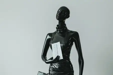 Черный манекен с сумочкой и книгой на белом фоне
