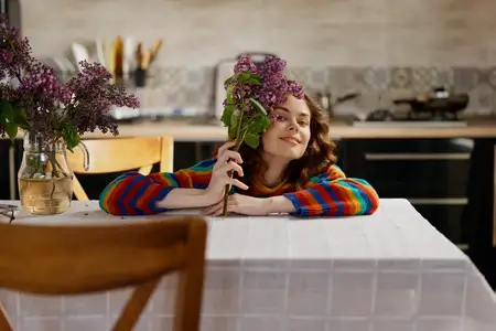 Повседневная домашняя сцена: расслабленная женщина с цветами на столе, яркий окружающий свет и жизнерадостное настроение, простой декор, повседневная жизнь, интимный естественный момент