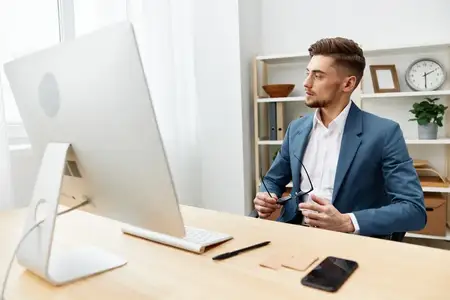 Менеджер работает за компьютером на рабочем столе, излучая уверенность в себе