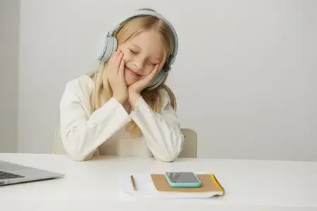Улыбающаяся девочка учится дома за ноутбуком