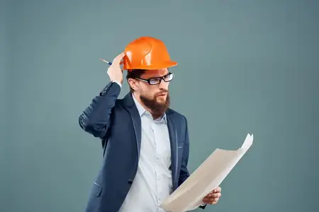 Бородатый мужчина держит в руках документы и чертежи, символизируя успех