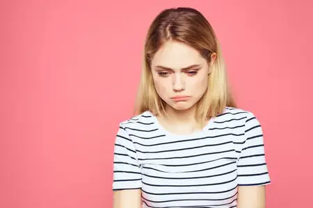 Блондинка в полосатой футболке выражает недовольство с помощью эмоций, жестов и рук