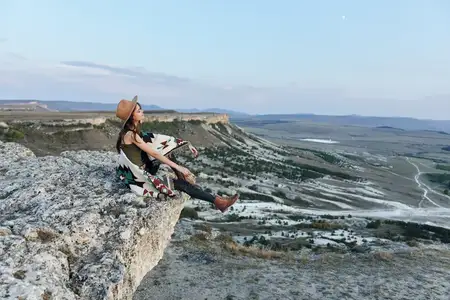 Женщина и собака наслаждаются видом с каменистого уступа над долиной