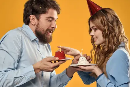 Мужчина и женщина веселятся на дне рождения на жёлтом фоне
