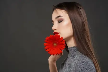 Брюнетка с красным цветком у лица, роскошная косметика, романтика