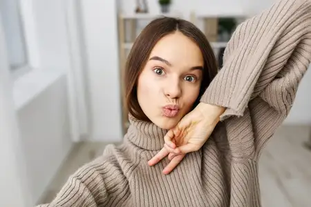 Женщина делает селфи на мобильный телефон, улыбаясь и позируя