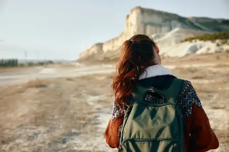 Безмятежный турист любуется величественной горой на бескрайнем поле в ясный день